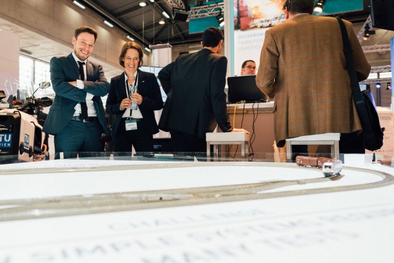 Trade fair visitors smiling as they watch the model railway at Transport Research Arena 2018