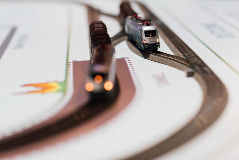Close-up of two illuminated model trains on tracks overlaid with projected graphics