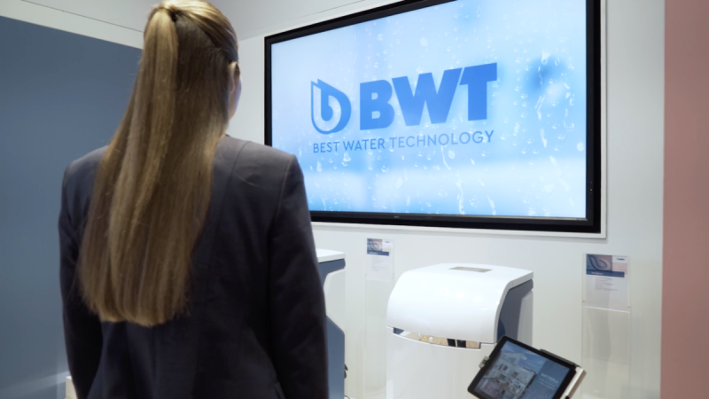 Besucherin vor großem Display mit BWT-Logo und Wasserenthärtungsanlage im Roadshow-Showroom