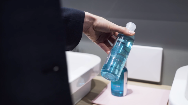 Hand nimmt eine Flasche aus dem Badregal der RFID-basierten Produktpräsentation