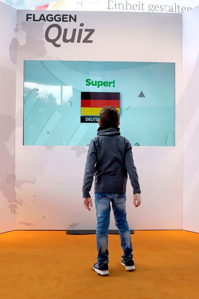 Junge vor dem Flaggenquiz-Screen, der die richtig gelegte deutsche Flagge mit „Super!“ bestätigt