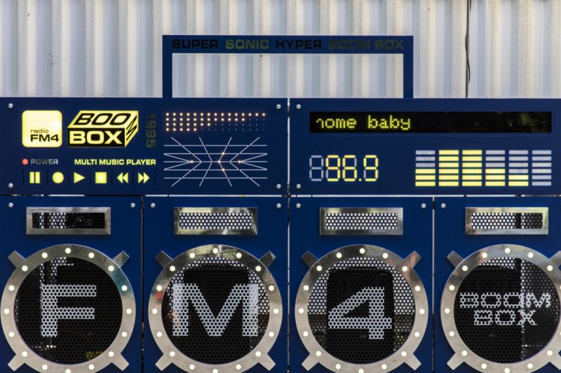 Retro-style control panel with Boombox logo, frequency display, equalizer bars and carrying handle