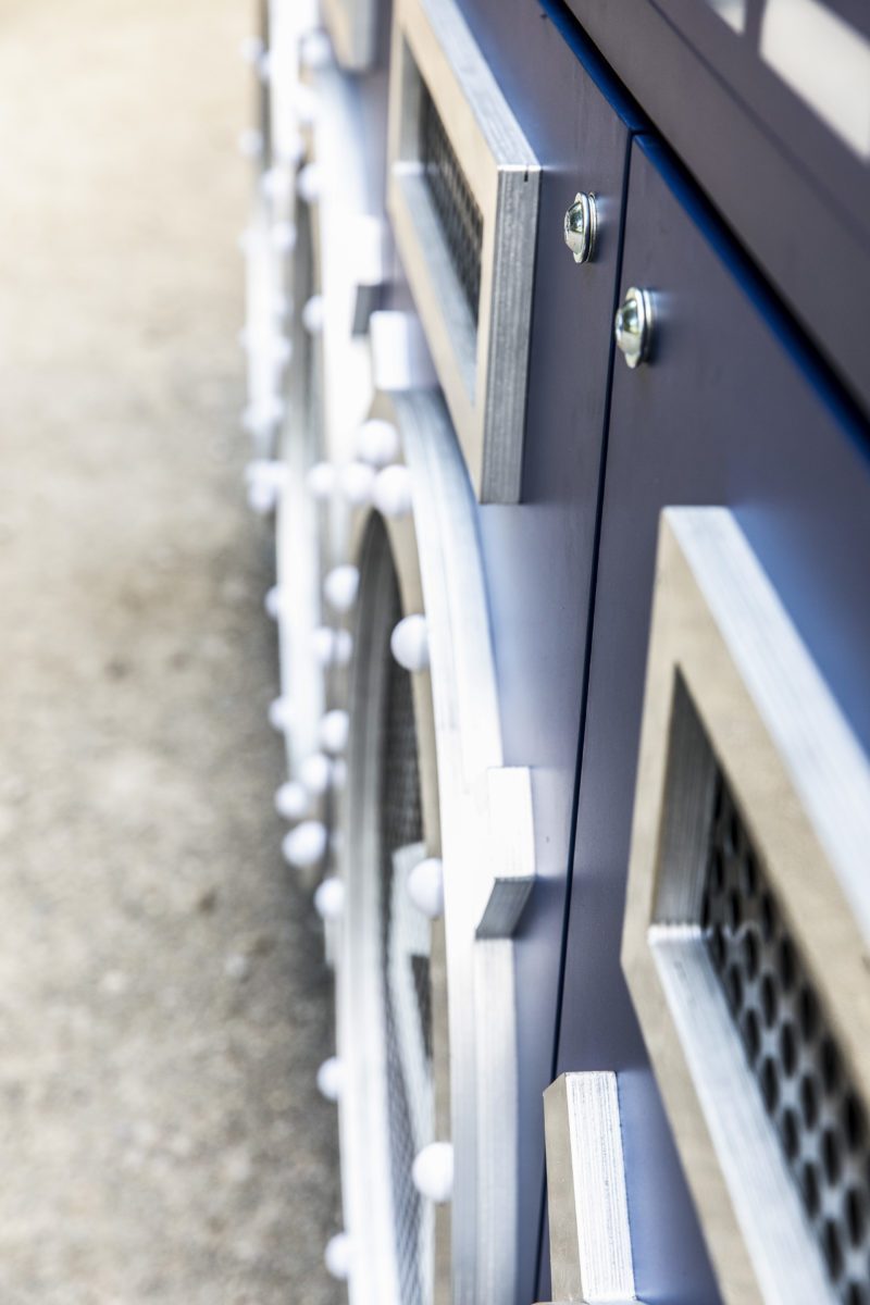Side detail of the blue front panels with aluminium frames, perforated metal and light points