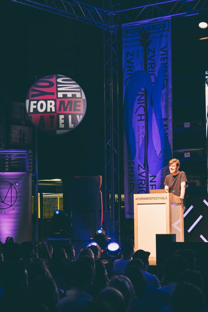 Sprecher am Pult mit #forwardfestivals, daneben ein bedruckter Ballon und ein Festivalbanner an der Traverse