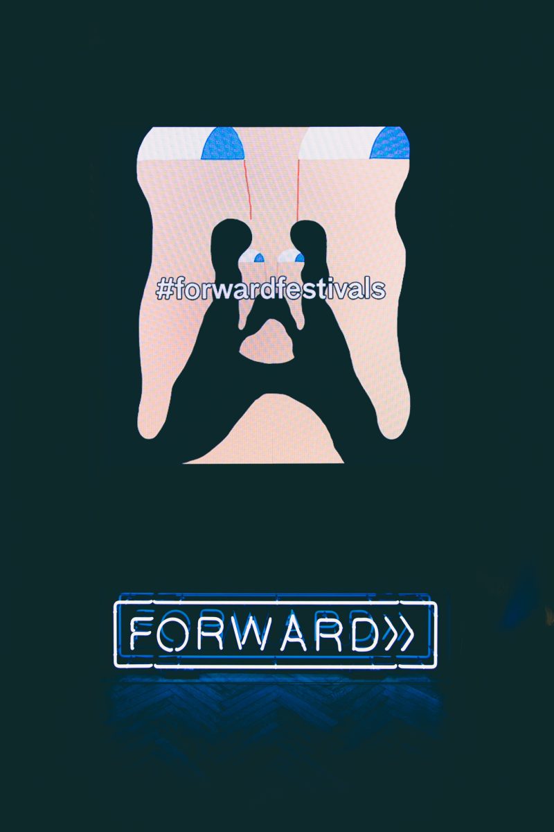 Screen mit Festival-Grafik und #forwardfestivals über einem Neonschriftzug „FORWARD“