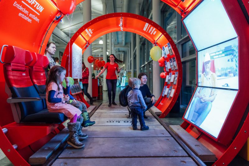 Kinder und Eltern in der InfoRail, rechts die Bildschirme einer interaktiven Videoinstallation