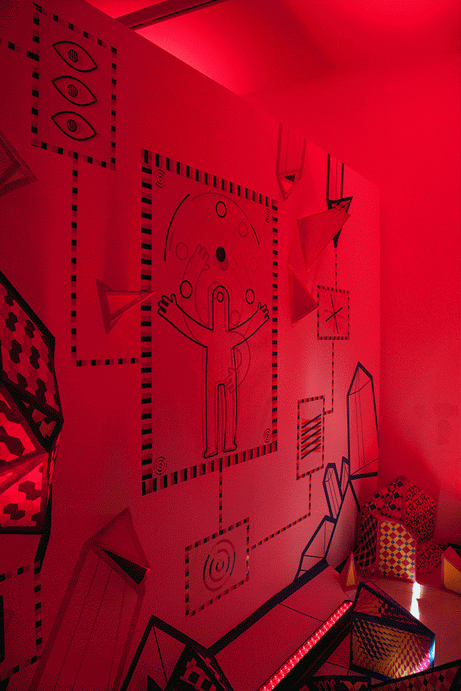 Mural with a figure, eye symbols and crystal shapes that changes under the coloured light