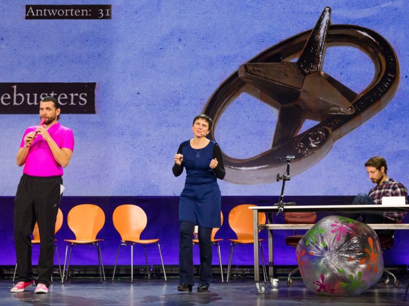 Host and performer with a recorder in front of a projected star emblem and an answer counter