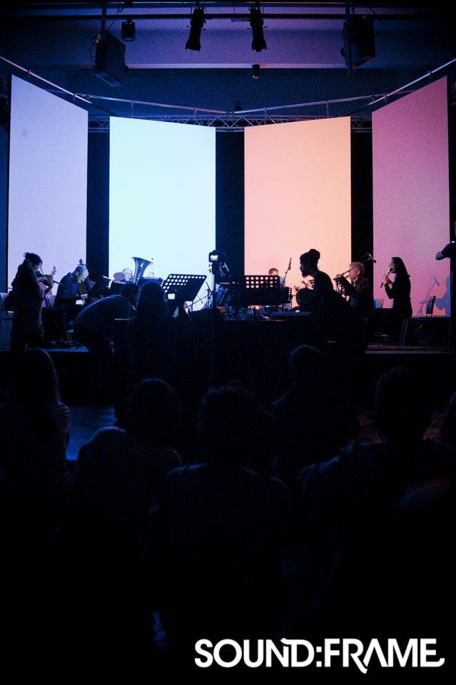 Ensemble spielt vor vier farbig beleuchteten Projektionsflächen beim sound:frame Festival
