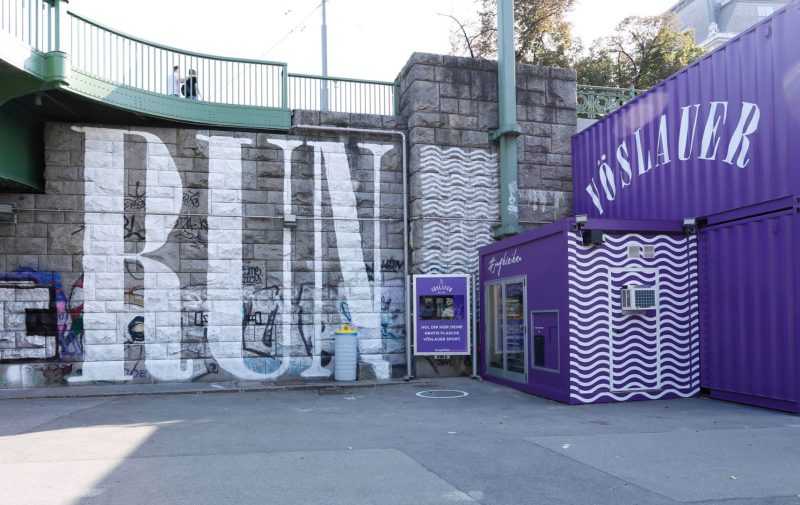 Vöslauer Laufomat on Vienna&#039;s Danube Canal: purple container marked #jungbleiben beside a wall painted “RUN”