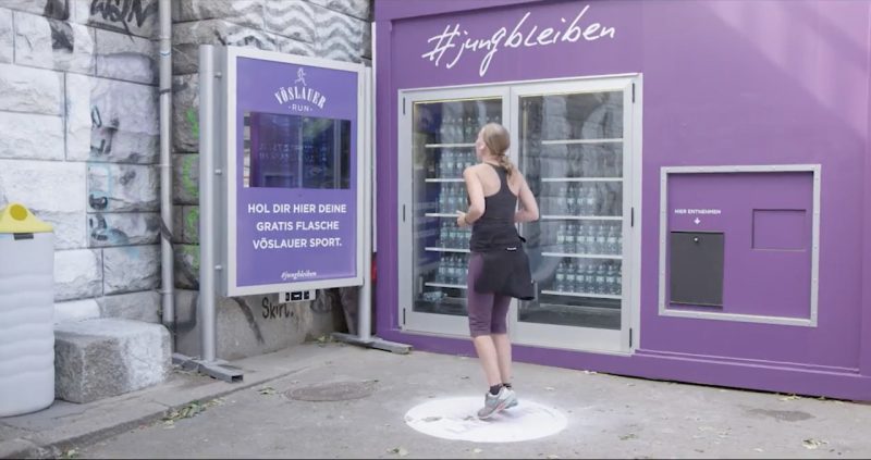 Videostill: Läuferin läuft auf der markierten Stelle vor dem Automaten, um eine Gratisflasche freizuschalten