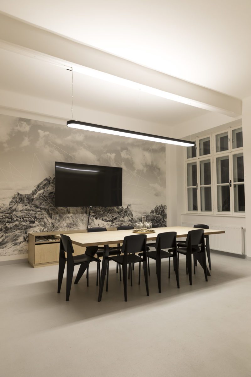 Meeting room at NBG31 with a long wooden table, black chairs, a screen and mountain photo wallpaper